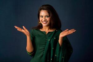 Portrait of a successful cheerful young girl presenting something with a fingers with a happy smiling face. photo