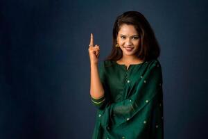 Portrait of a successful cheerful young girl presenting something with a fingers with a happy smiling face. photo