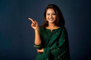 Portrait of a successful cheerful young girl presenting something with a fingers with a happy smiling face. photo