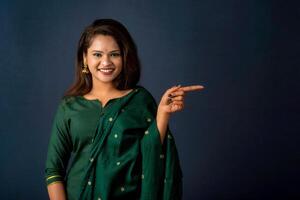Portrait of a successful cheerful young girl presenting something with a fingers with a happy smiling face. photo