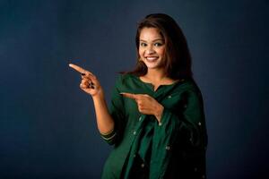 Portrait of a successful cheerful young girl presenting something with a fingers with a happy smiling face. photo