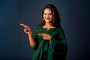 Portrait of a successful cheerful young girl presenting something with a fingers with a happy smiling face. photo