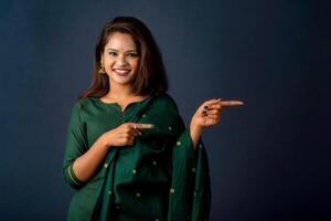 Portrait of a successful cheerful young girl presenting something with a fingers with a happy smiling face. photo