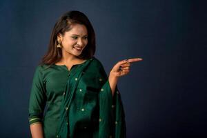Portrait of a successful cheerful young girl presenting something with a fingers with a happy smiling face. photo
