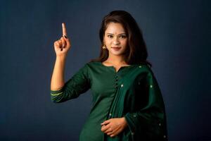 Portrait of a successful cheerful young girl presenting something with a fingers with a happy smiling face. photo
