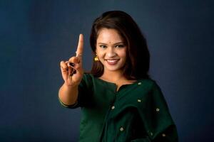 Portrait of a successful cheerful young girl presenting something with a fingers with a happy smiling face. photo
