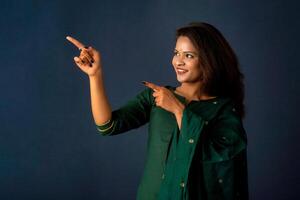 Portrait of a successful cheerful young girl presenting something with a fingers with a happy smiling face. photo