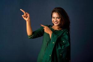 Portrait of a successful cheerful young girl presenting something with a fingers with a happy smiling face. photo