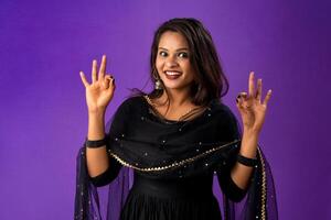 Young smiling girl showing ok sign or thumbs up on a grey background photo