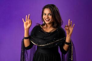 Young smiling girl showing ok sign or thumbs up on a grey background photo