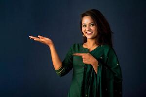 Portrait of a successful cheerful young girl holding and presenting something on hand with a happy smiling face. photo