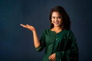 Portrait of a successful cheerful young girl holding and presenting something on hand with a happy smiling face. photo