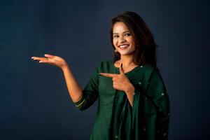 Portrait of a successful cheerful young girl holding and presenting something on hand with a happy smiling face. photo