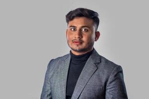 Portrait of Happy Indian young man, businessman wearing a blazer on grey background posing, satisfied successful male in formal suit photo