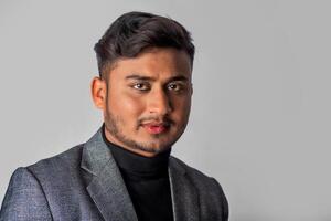 Portrait of Happy Indian young man, businessman wearing a blazer on grey background posing, satisfied successful male in formal suit photo