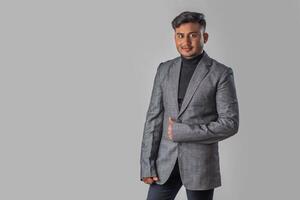 Portrait of Happy Indian young man, businessman wearing a blazer on grey background posing, satisfied successful male in formal suit photo