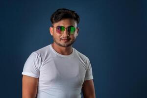 Portrait of Happy Indian young man with eyeglasses posing on a blue background photo