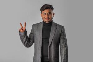 Portrait of a successful cheerful young man wearing formal suit pointing and presenting something with hand or finger with a happy smiling face. photo