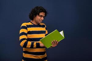 Young happy man holding and posing with the book on gray background. photo