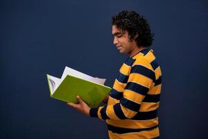 Young happy man holding and posing with the book on gray background. photo