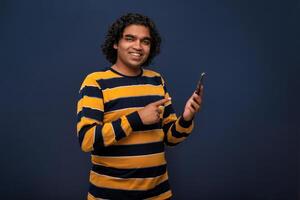 Young handsome young man holding and using smartphone or mobile or tablet phone on grey background photo