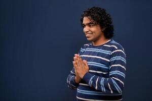 Young Indian man with welcome expression or inviting or greeting Namaste on dark background photo