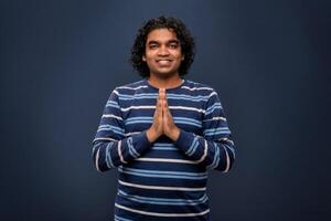 Young Indian man with welcome expression or inviting or greeting Namaste on dark background photo