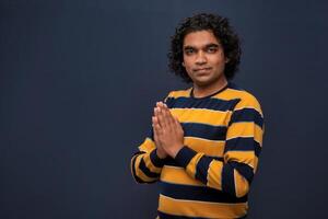 Young Indian man with welcome expression or inviting or greeting Namaste on dark background photo