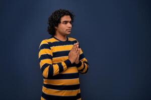 Young Indian man with welcome expression or inviting or greeting Namaste on dark background photo