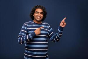 Portrait of a successful cheerful young man pointing and presenting something with hand or finger with a happy smiling face. photo