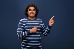 Portrait of a successful cheerful young man pointing and presenting something with hand or finger with a happy smiling face. photo