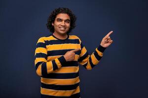 Portrait of a successful cheerful young man pointing and presenting something with hand or finger with a happy smiling face. photo