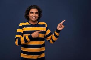 Portrait of a successful cheerful young man pointing and presenting something with hand or finger with a happy smiling face. photo