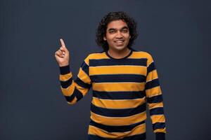 Portrait of a successful cheerful young man pointing and presenting something with hand or finger with a happy smiling face. photo
