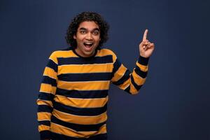 Portrait of a successful cheerful young man pointing and presenting something with hand or finger with a happy smiling face. photo