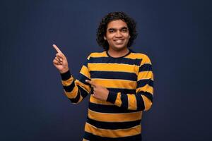 Portrait of a successful cheerful young man pointing and presenting something with hand or finger with a happy smiling face. photo