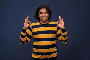 Portrait of a successful cheerful young man pointing and presenting ok, victory sign with hand or finger with a happy smiling face. photo