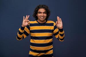 Portrait of a successful cheerful young man pointing and presenting ok, victory sign with hand or finger with a happy smiling face. photo
