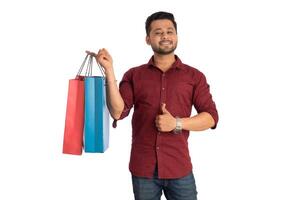 Young handsome man holding and posing with shopping bags on a white background photo
