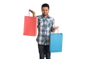 Young handsome man holding and posing with shopping bags on a white background photo