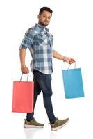 Young handsome man holding and posing with shopping bags on a white background photo