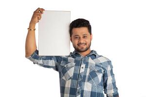 A happy young man holding and displaying a signboard or placard in his hands on a white background. photo