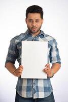 A happy young man holding and displaying a signboard or placard in his hands on a white background. photo