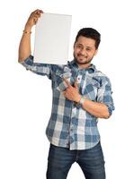 A happy young man holding and displaying a signboard or placard in his hands on a white background. photo