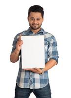 A happy young man holding and displaying a signboard or placard in his hands on a white background. photo