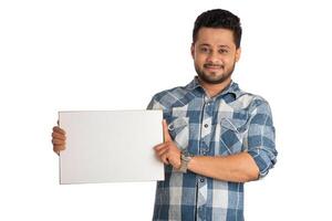 A happy young man holding and displaying a signboard or placard in his hands on a white background. photo
