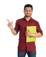 Young happy man holding and posing with the book on white background. photo
