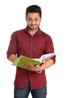 Young happy man holding and posing with the book on white background. photo