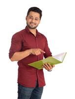 Young happy man holding and posing with the book on white background. photo