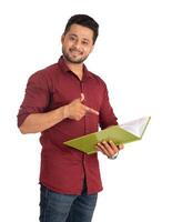 Young happy man holding and posing with the book on white background. photo